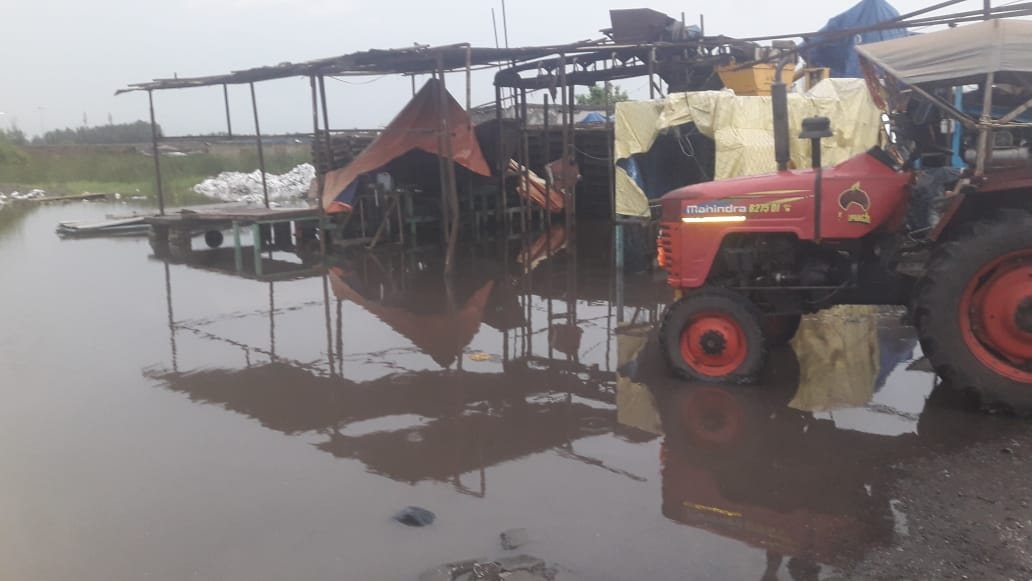 Flooded site plant yard at Dhamra with a tractor standing in water