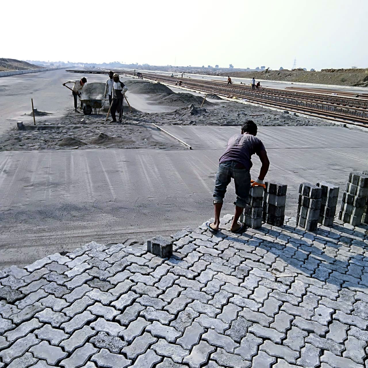 Paver blocks being manufactured and laid at a large infrastructure project site