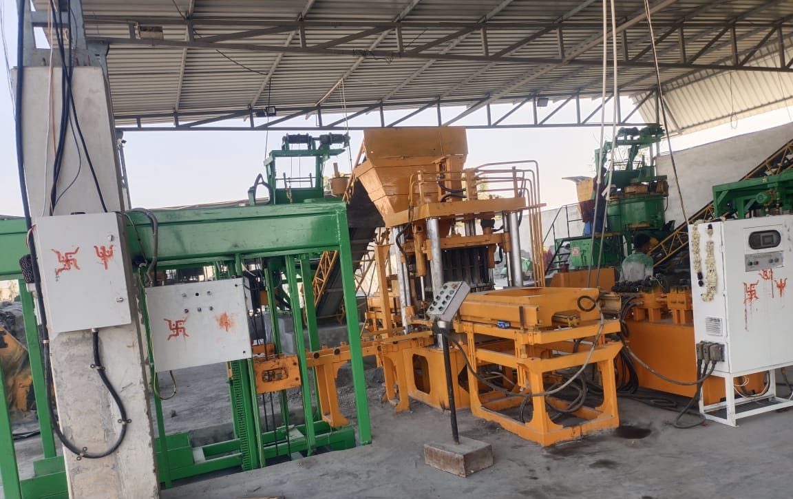 Yellow block-making presses and green pallet frames on a production line